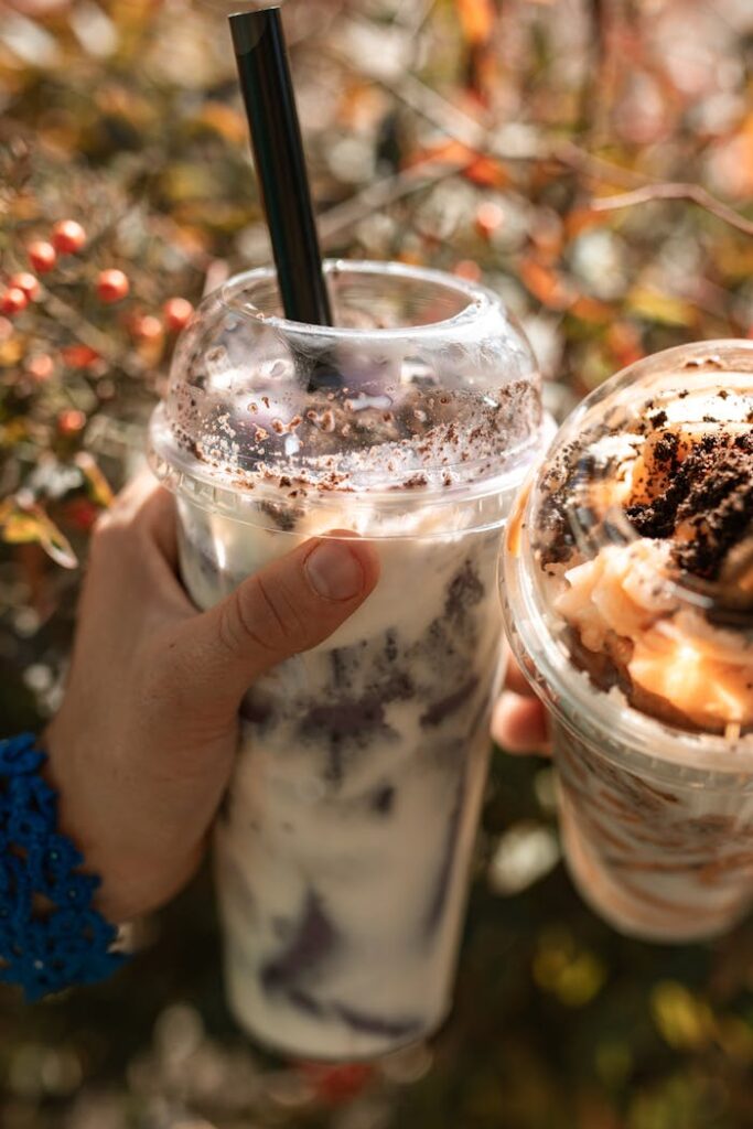 Close-up of boba tea and dessert cups held outdoors, bright and refreshing.